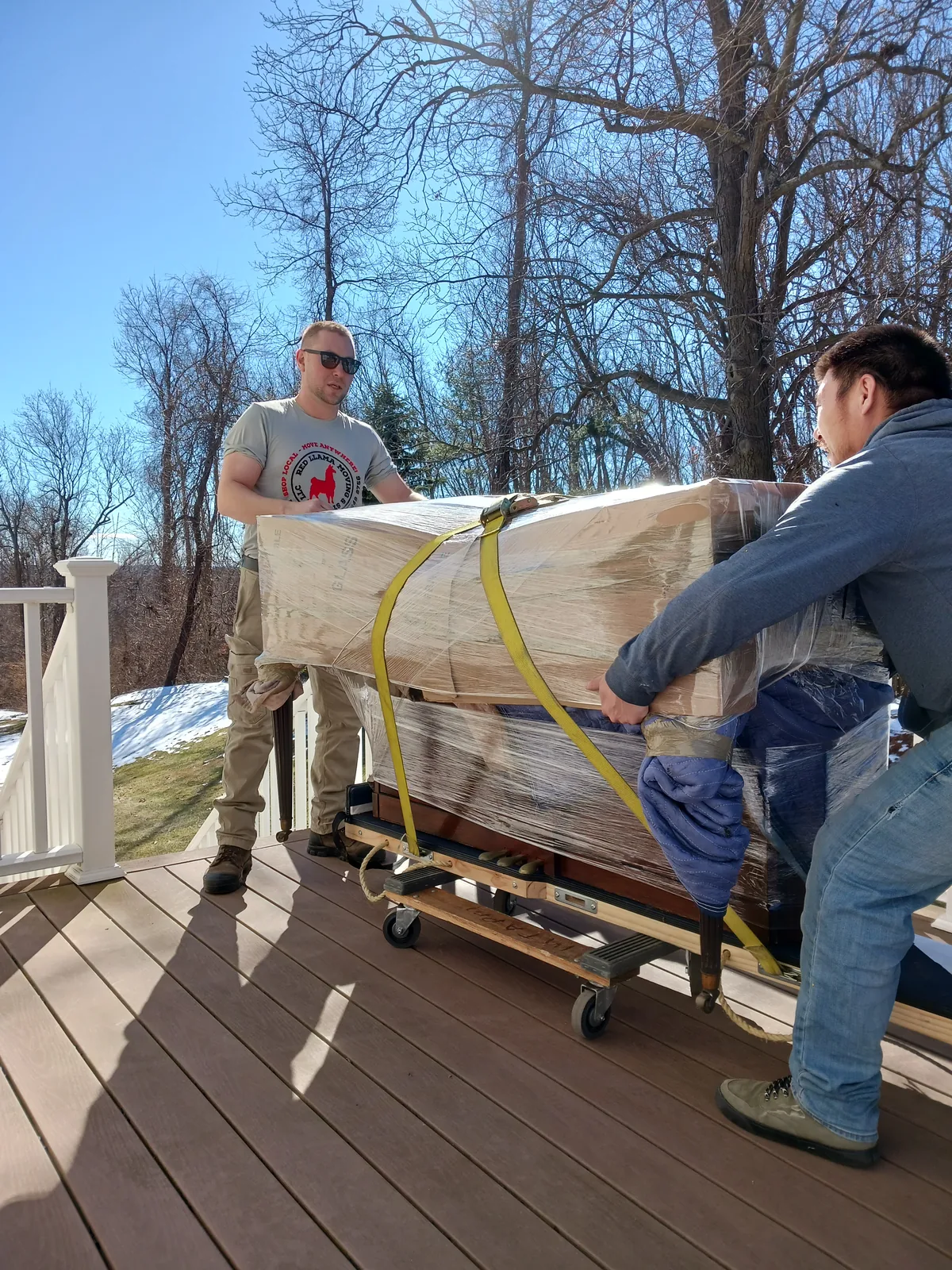 Red Llama movers guiding a protected household item at a home.