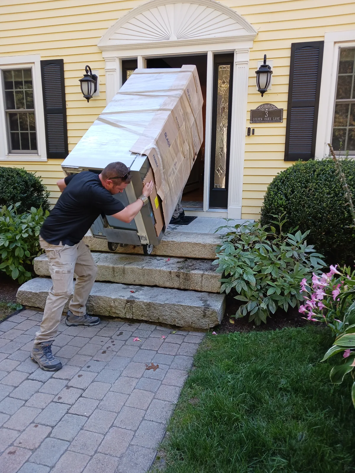 Red Llama mover guiding a large wrapped household item through a home entrance.