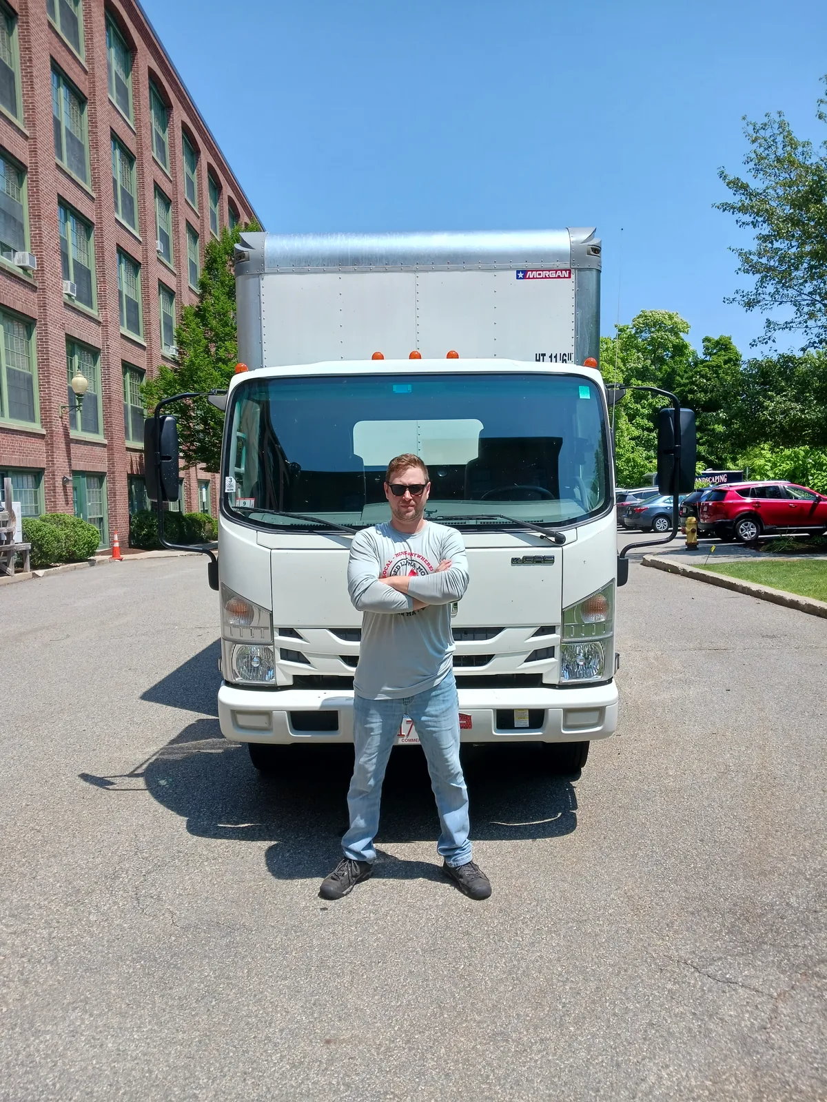 Red Llama mover standing in front of the branded truck beside a brick building.